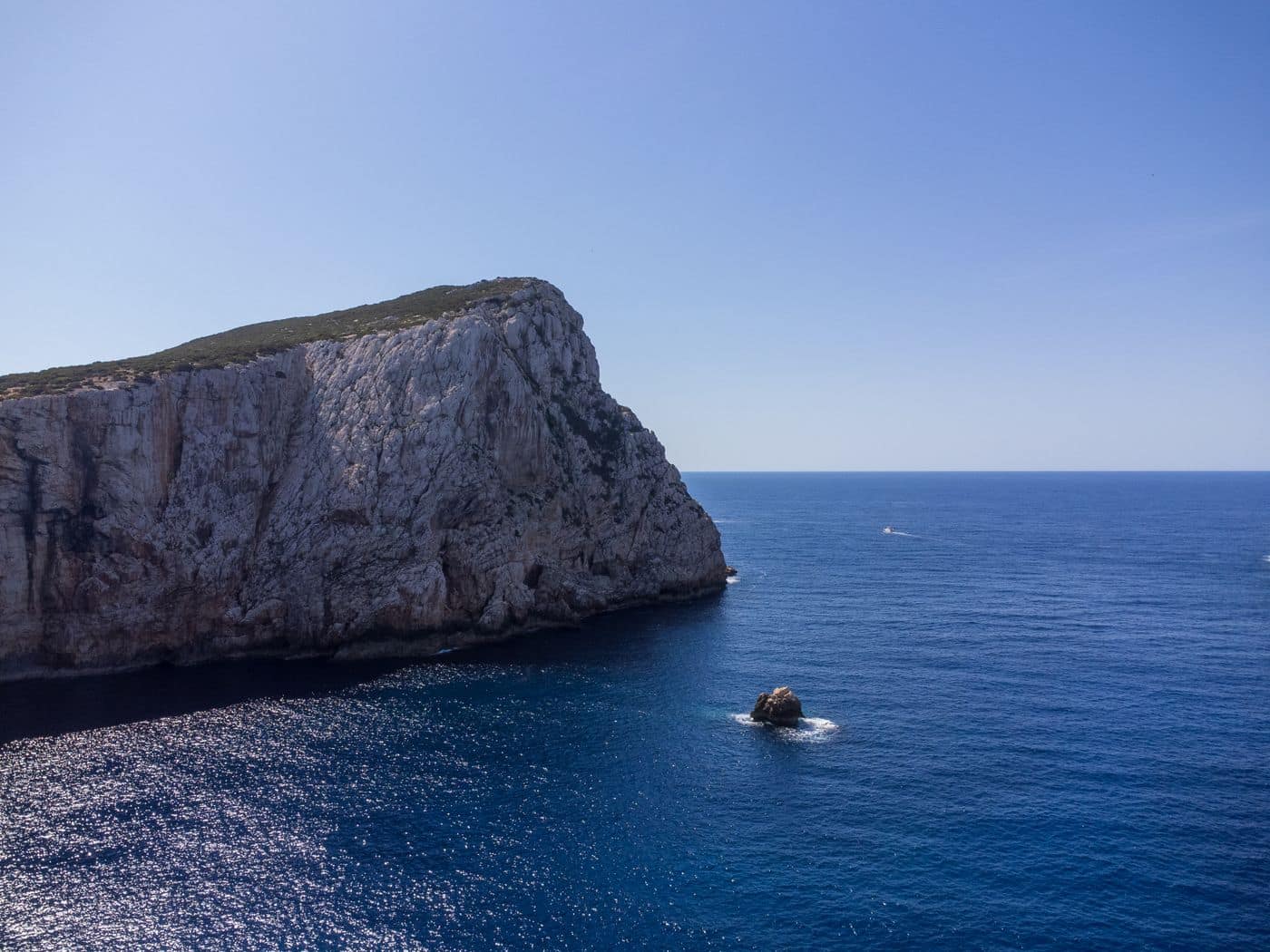 The rocky Sardinian coastline above clear water near the school's cove.