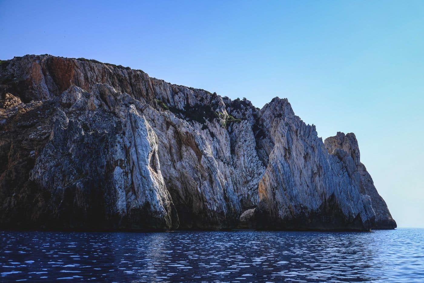 A limestone headland rising from the deep blue sea of the Gulf of Orosei.