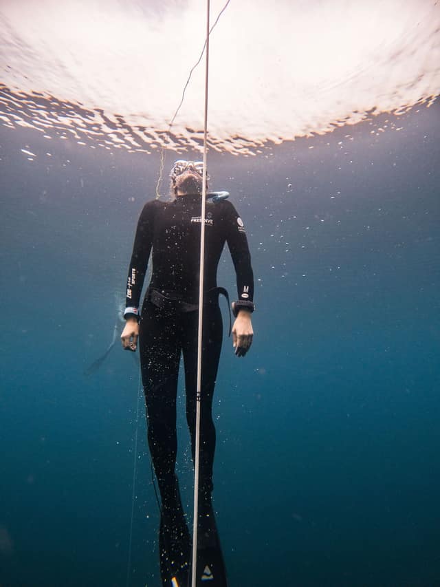 A diver suspended in clear open sea, weightless and still.
